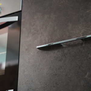 Moderne Küchenzeile mit schwarzen Küchenfronten Elektrogeräten und Edelstahl Griffen