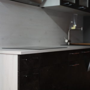 Moderne Küchenzeile mit weißer Arbeitsplatte schwarzen Küchenfronten Oberschrank mit Glas Türen