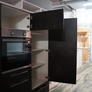 Moderner Wandschrank mit schwarzen Fronten Elektrogeräten